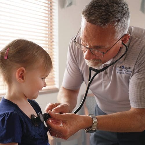 Dr. Poock checking a female child's heart rate